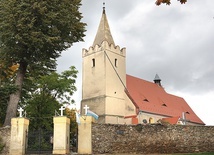 ▲	Kościół parafialny otacza mur z kamienia polnego, odłamków skalnych i cegły.