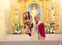 Bp Piotr Libera udziela błogosławieństwa księgą Ewangelii.