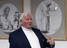 Ks. Stanisław Drąg na tle swych rysunków, które przedstawiają Jana Pawła II.