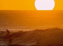 Mężczyzna surfujący na Hawajach o zachodzie słońca. 
28.01.2020 Plaża na wyspie Oahu, Stany Zjednoczone