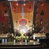 ▲	Widok na główny ołtarz. W tle Maryja w charakterystycznej postawie orantki.