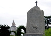 Kamienny monument przypominający o krzyżu na Giewoncie, ustawiony w Ogrodach Watykańskich z woli św. Jana Pawła II w 2001 r. W tle kopuła bazyliki św. Piotra.