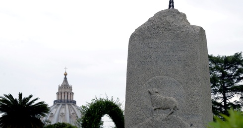 Kamienny monument przypominający o krzyżu na Giewoncie, ustawiony w Ogrodach Watykańskich z woli św. Jana Pawła II w 2001 r. W tle kopuła bazyliki św. Piotra.