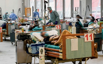 Lekarze, pielęgniarki i inni pracownicy szpitali z narażeniem życia niosą pomoc osobom chorującym z powodu COVID-19.