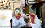 Cierpienie i skupienie wymalowane na twarzy biskupa ukazującego wiernym krzyż.