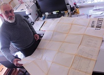 Pan Jerzy w swojej pracowni pokazuje oryginalne plany umiejscowienia konstrukcji ołtarzowej na legnickim lotnisku.