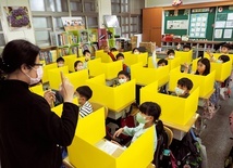 Uczniowie oddzieleni od siebie ściankami z plastiku uczestniczą w zajęciach w szkole podstawowej Dajia w Tajpej. 3.03.2020 Tajwan