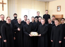 Klerycy podczas spotkania mogli również skosztować tort, który miał kształt księgi Pisma Świętego. Z tortem stoi ks. Jacek Kucharski (z prawej)