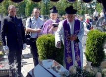 Ks. Bogusław Wermiński posypujący ziemią trumnę zmarłego szafarza.