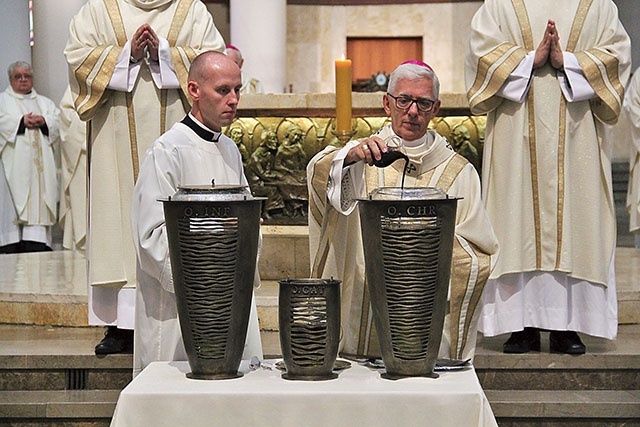 Abp Wiktor Skworc wlewa balsam, przygotowując olej krzyżma.