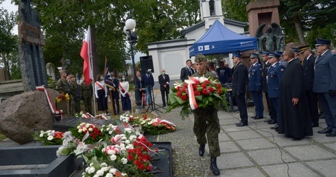 Kwiaty przy pomniku katyńskim składają przedstawiciele służb mundurowych.