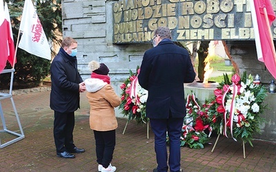 ▲	Złożenie kwiatów pod pomnikiem przez przedstawicieli rodzin poległych.