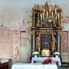 ▼	Na ścianie wschodniej (po lewej) widoczny jest napis „Maria”, pod nim polichromia imitująca tkaninę otacza niezamalowany kształt, który mogła wyznaczyć przysunięta do ściany Pieta.