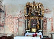 ▼	Na ścianie wschodniej (po lewej) widoczny jest napis „Maria”, pod nim polichromia imitująca tkaninę otacza niezamalowany kształt, który mogła wyznaczyć przysunięta do ściany Pieta.