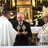 ▲	Prowincjał w obecności biskupa wręcza relikwiarze dr. Jerzemu Miszkiewiczowi, prezesowi stowarzyszenia.