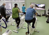 Rehabilitacja pocovidova w Głuchołazach. Wśród aktywności jest jazda na rowerze przy obserwowaniu dynamicznie zmieniających się krajobrazów na ekranie telewizora.