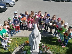 Przed Maryją, z bukietami wiosennych majowych kwiatów.