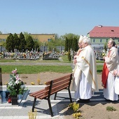 Modlitwa przy krzyżu na cmentarzu parafialnym. W tle budynki schroniska.