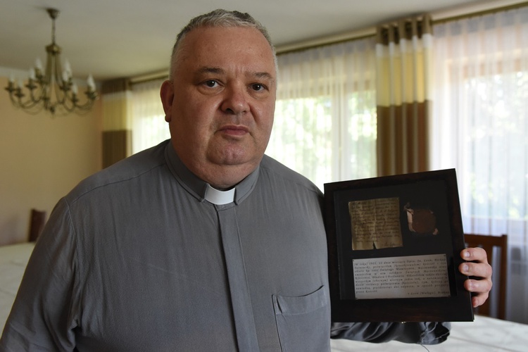 Ks. proboszcz Piotr Lisowski prezentuje list arcybiskupa Wałęgi sprzed 100 lat.