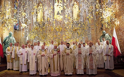 ▼	Pamiątkowe zdjęcie kapłanów przy bursztynowym ołtarzu.