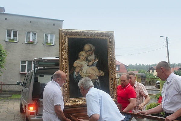 Mężczyźni wnieśli obraz do kościoła.