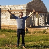 Stefan na tle rozbudowanej szkoły, która czeka na dach.
