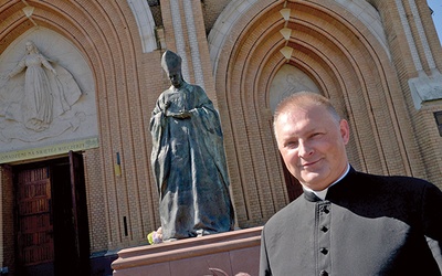 Ksiądz Marcin Rogala przy pomniku Prymasa Tysiąclecia, który stoi przed radomską katedrą.