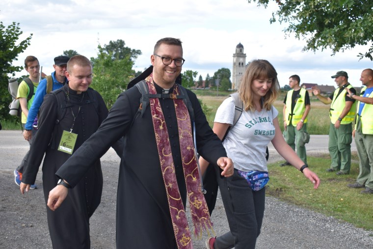 Uśmiechnięci pielgrzymi dochodzący do postoju.