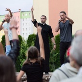 Ks. Dawid Fiołek na scenie z zespołem raperów.