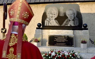 Biskup przed pomnikiem upamiętniającym ważne wizyty w historii sanktuarium.