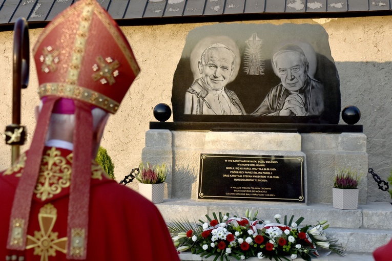 Biskup przed pomnikiem upamiętniającym ważne wizyty w historii sanktuarium.