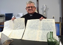 Ks. Andrzej Margas pokazuje archiwalia odkryte podczas prac przy montowaniu instalacji przeciwpożarowej w zabytkowej świątyni. 