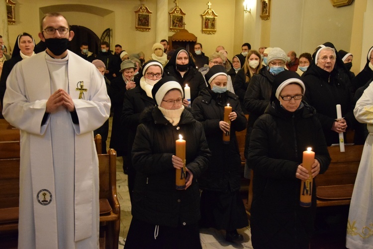 Osoby zakonne złożyłe na ręce biskupa zapalone świece.