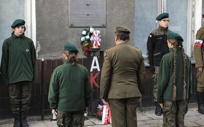 Złożenie kwiatów przed pamiątkową tablicą.