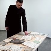 	Ksiądz Sebastian Kapuściński prezentuje część odnalezionych zbiorów.