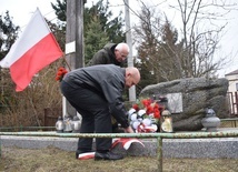 Składanie kwiatów przed pamiątkową tablicą.