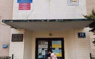 	Uśmiechnięte bohaterki przed wejściem do ukraińskiej szkoły.
