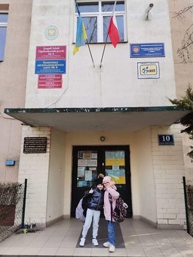 	Uśmiechnięte bohaterki przed wejściem do ukraińskiej szkoły.