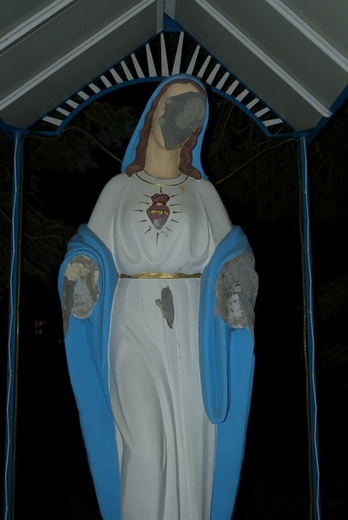 Zniszczona figura Matki Bożej na placu przykościelnym.