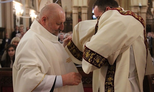 Ks. proboszcz Andrzej Zając pomaga nałożyć dalmatykę diakonowi Adamowi Płonce.