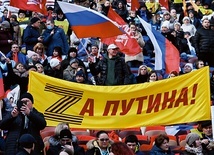 Demonstracja wsparcia dla wojny na Ukrainie.Stadion Łużniki, Moskwa, 18 marca 2022 r.  Na transparencie wykorzystany został znak „Z” – symbol agresji – rozwinięty w hasło: „Za Putina”. Literę „Z” tworzy tzw. wstążka św. Jerzego, symbolizująca zwycięstwo nad III Rzeszą.