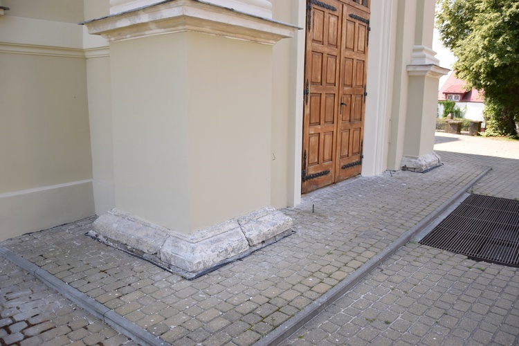 Osłonięte elementy kamienne przy fasadzie kościoła.