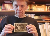 Malarz trzyma rodzinne zdjęcie. Widać na nim m.in. stojących  przy wielkanocnym stole Antoniego i świętego franciszkanina.