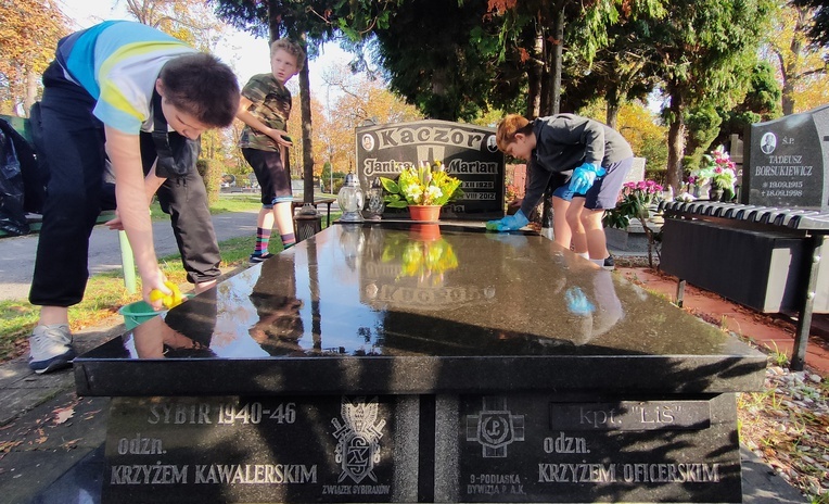 Młodzi kibice sprzątają groby