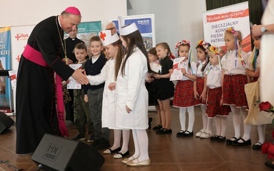 Nagrodę zespołowi Patriotyczne Zajączki wręcza bp Marek Solarczyk.