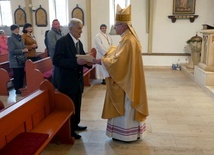 Biskup składający odchodzącemu na emeryturę kościelnemu gratulacje.