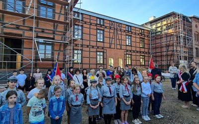 Najmłodsi uczestnicy pielgrzymki na tle dawnych budynków obozowych, które obecnie są poddane konserwacji.