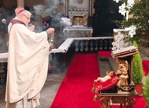 Biskup okadza figurkę Dzieciątka Jezus.