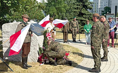 ▲	Kwiaty przed tablicą składają przedstawiciele wojska.
