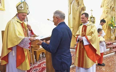 Bp Andrzej Jeż przekazuje papieski dokument wójtowi Janowi Dydzie.